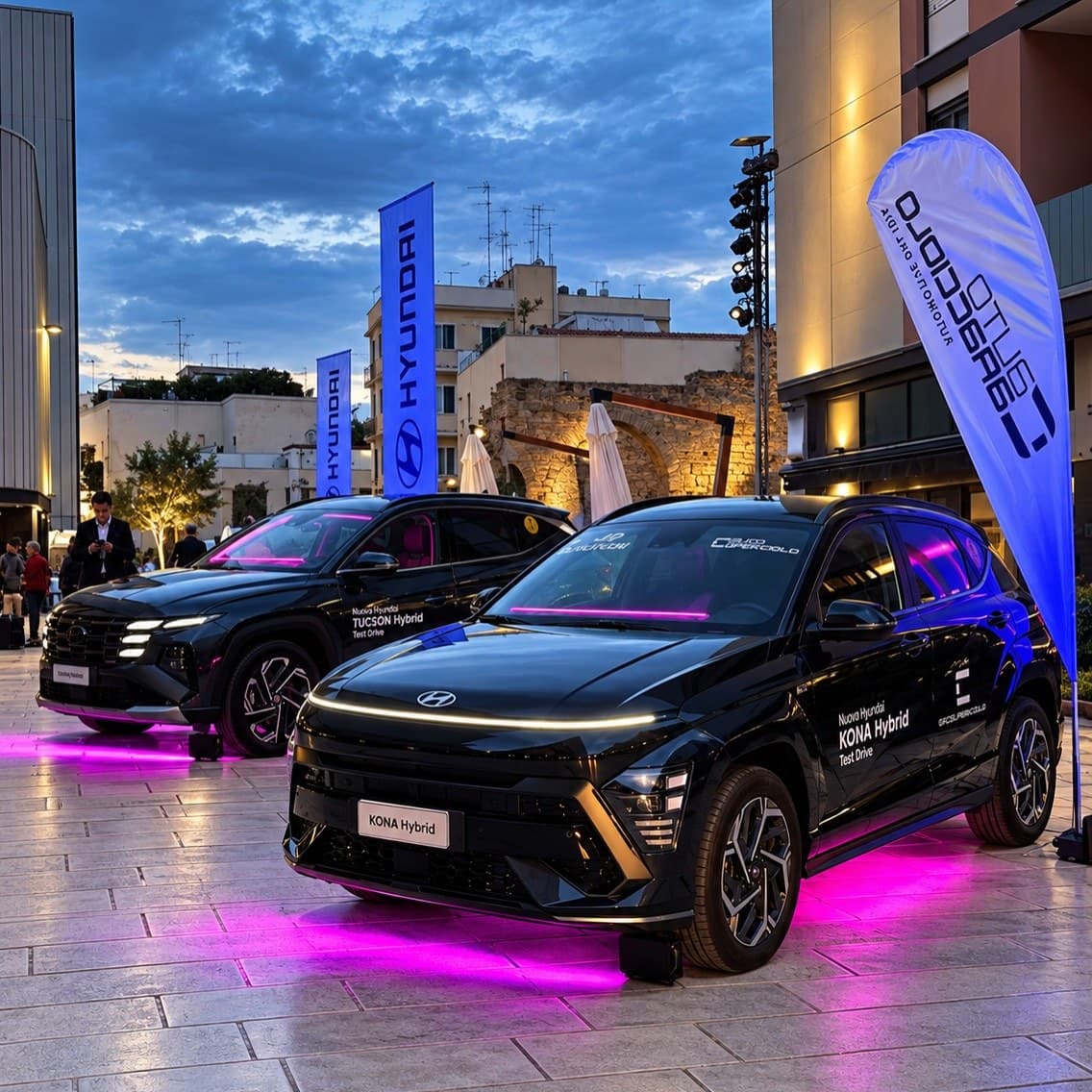 Auto illuminate da sotto con barre LED magenta durante una presentazione in piazza, all'imbrunire