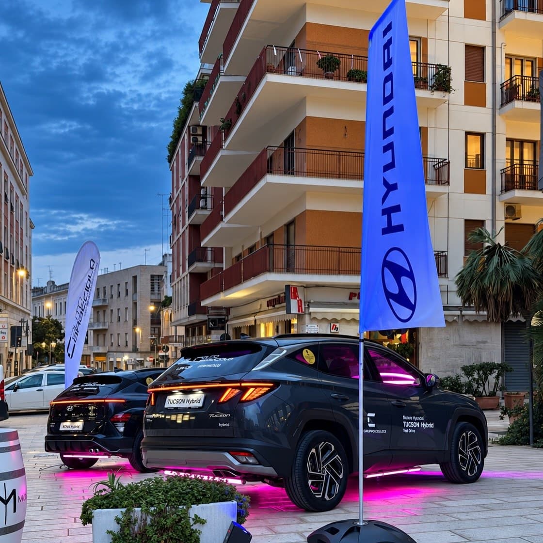 La stessa presentazione vista di lato, con le bandiere e le auto illuminate fra i palazzi